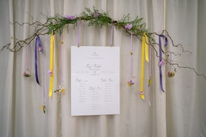 Whimsical hanging table plan with purple and yellow ribbon