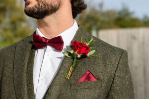 Three piece tweed wedding suit with red pocket square and button hole